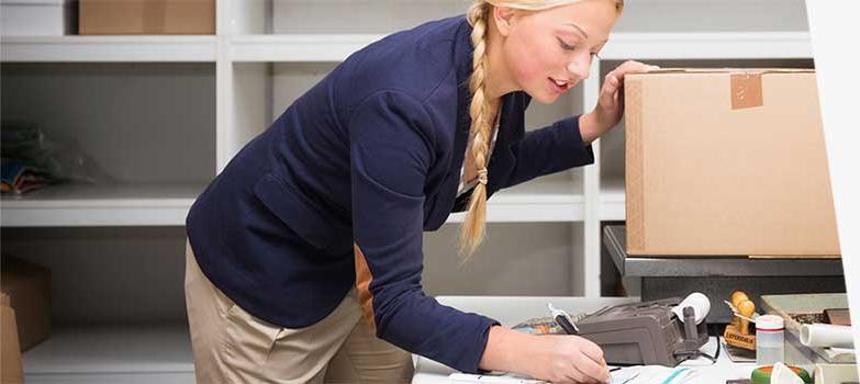 Woman checking shipping box weight and postage.